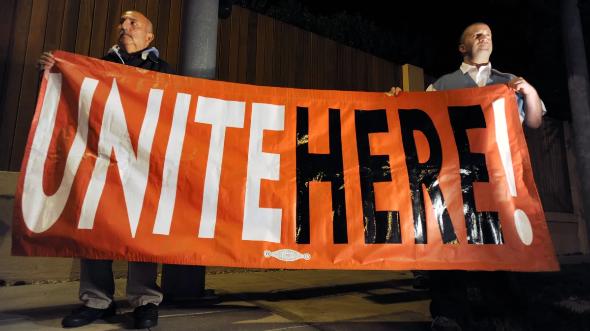 Two people holding up sign that reads Unite Here