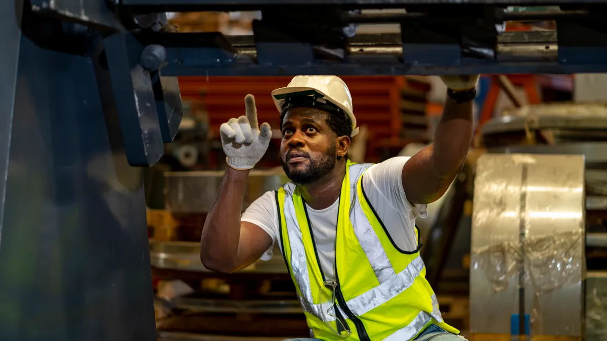 A maintenance worker inspects a machine inside a manufacturing facility.