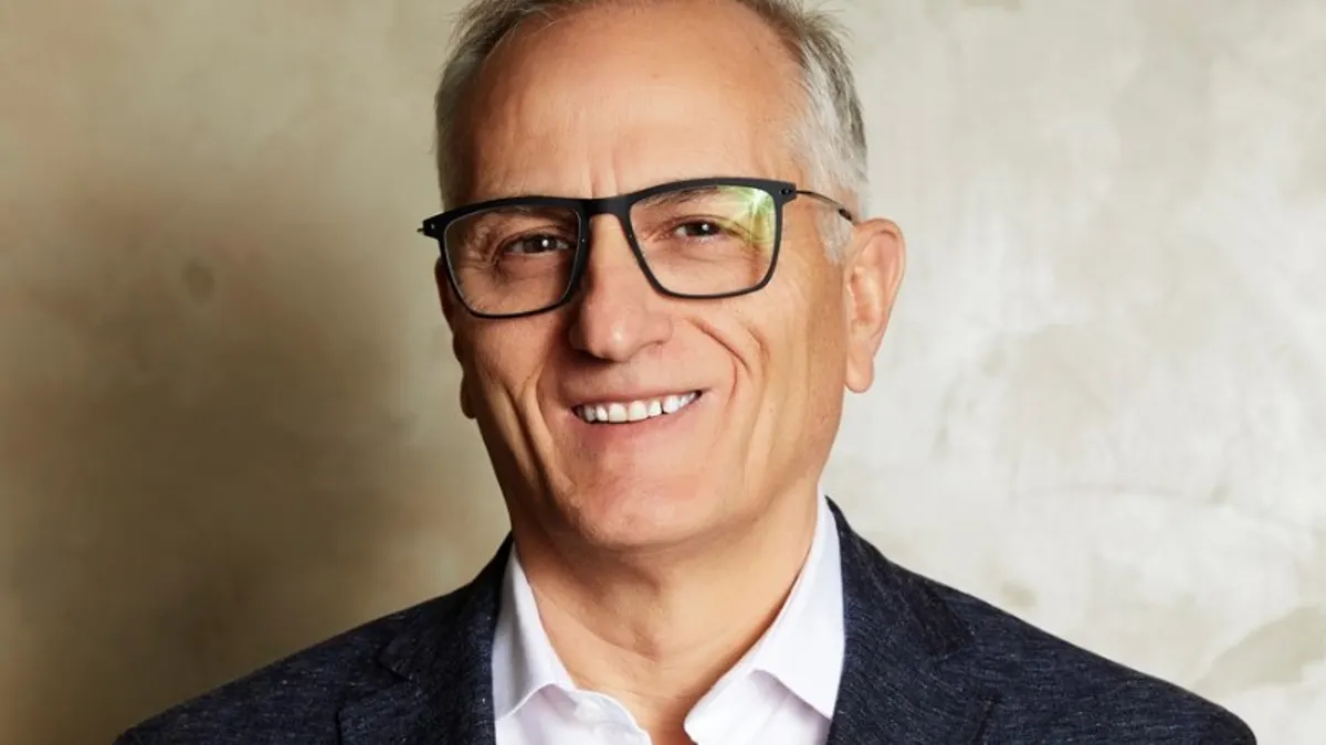 A person in a business suit faces the camera for a photograph.