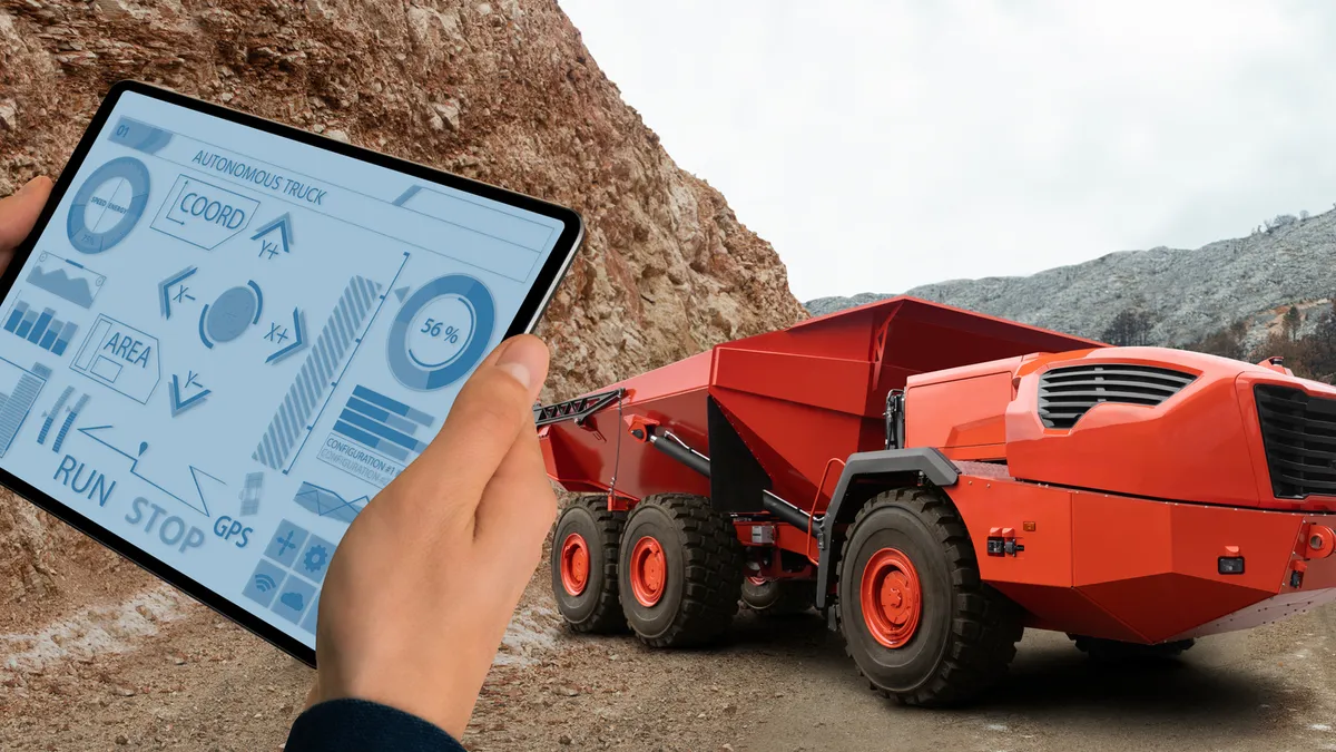 Man controls autonomous mining truck using digital tablet