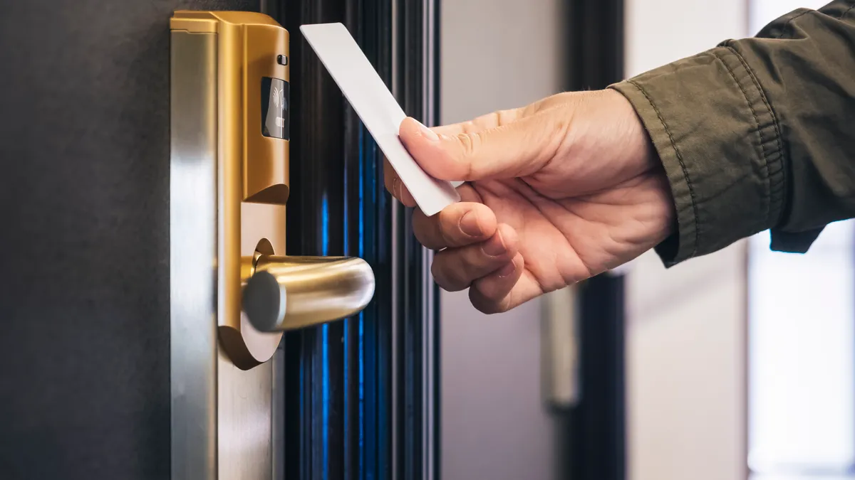 Person holds hotel key to door