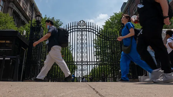 A few pedestrians walk by Columbia University's gates.