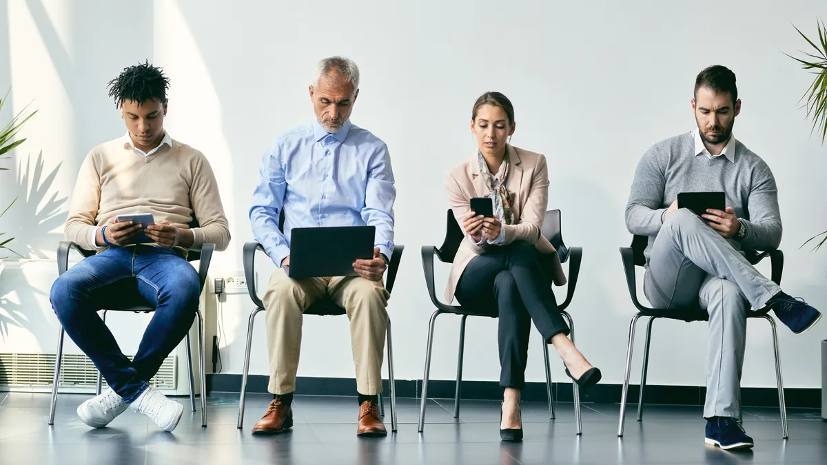 Small group of business people using wireless technology while anticipating job interview.