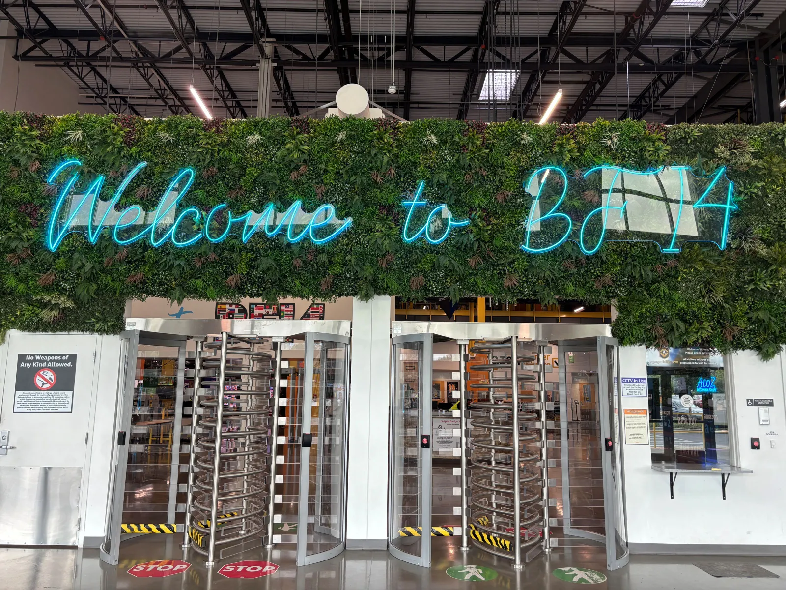 A “welcome to BFI4” illuminated sign sits against a plant background above a revolving door.
