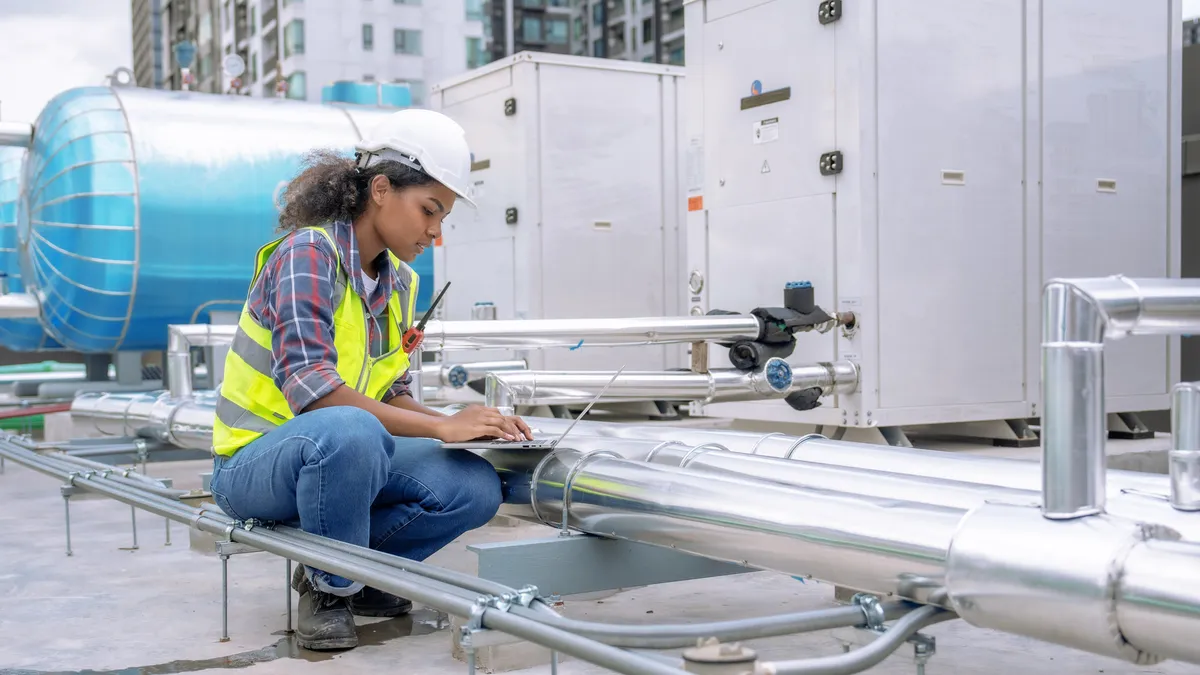 A female engineer inspects and controls the cooling system of a large factory air conditioner