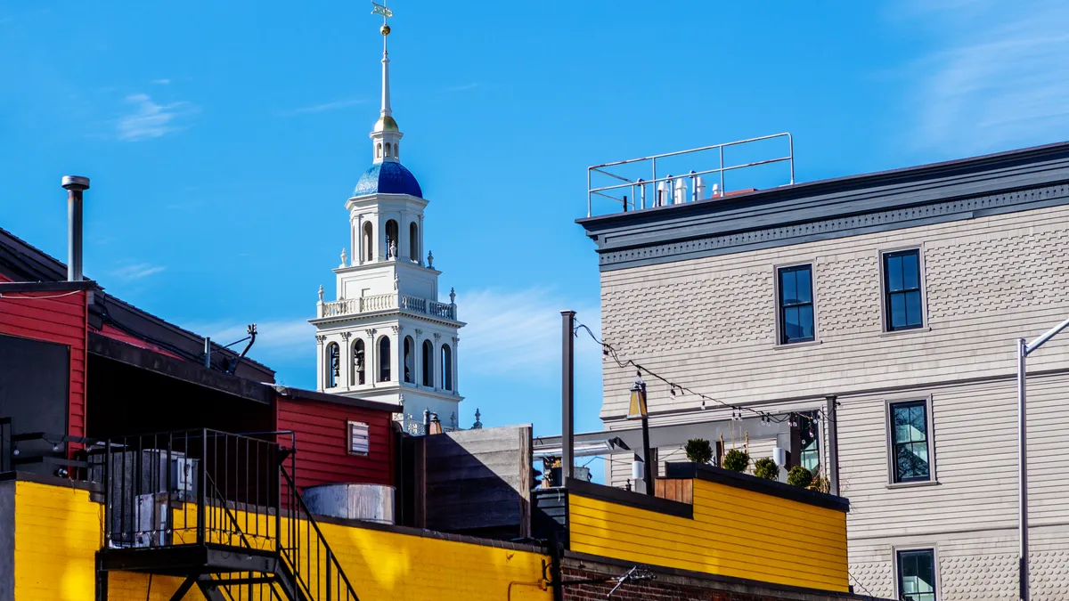 Roofs of three buildings against a blue sky