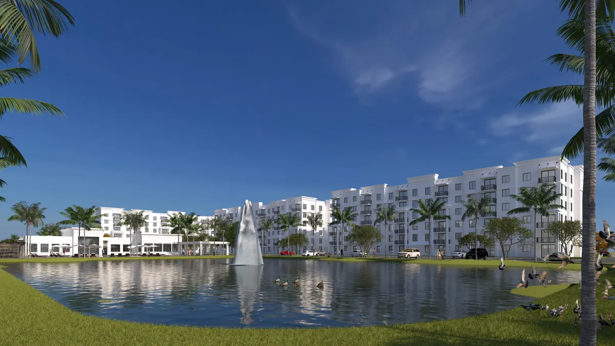 White mid-level apartment property with a lake in the foreground.