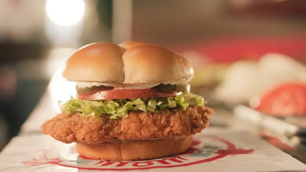 A fast food chicken sandwich with a breaded cutlet, soft potato bun, mayo, tomatoes and pickles.