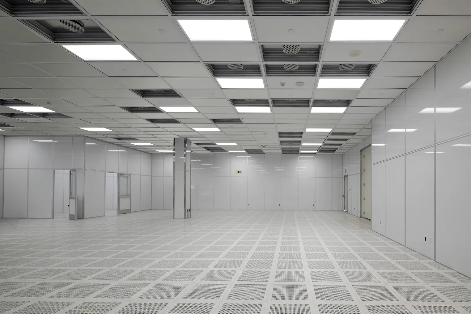 An empty, white room with fluorescent lighting and columns.