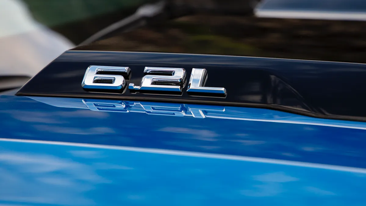 A close up view of a "6.2L" badge on the hood of a blue 2022 Chevy Silverado.