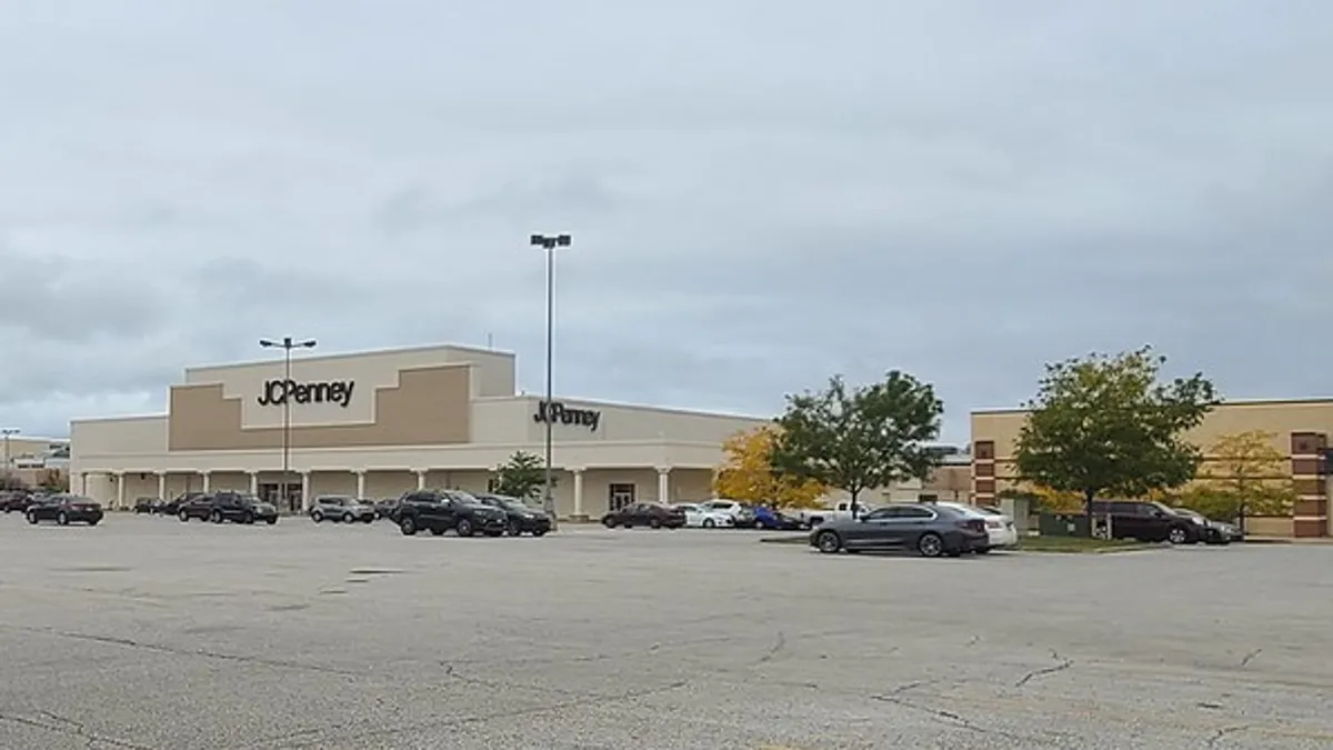 A shopping mall with cars parked in the lot and a few trees.