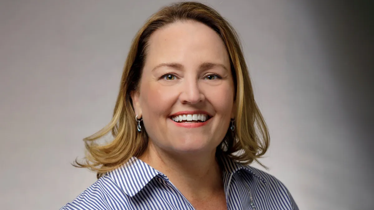 An image of a woman smiling wearing a blue suit.