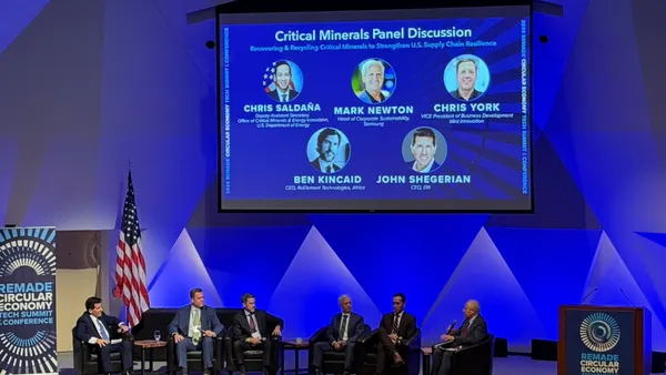 speakers sit on a stage with a projection screen above them