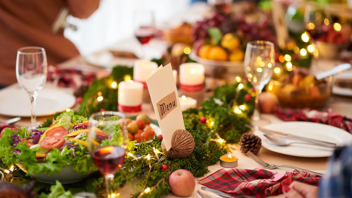 Close-up of a table set up for a holiday meal with red and black checkered napkins, a salad bowl and sparkling glasses.