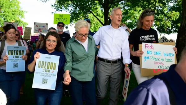 A line of people linking arms and holding signs.