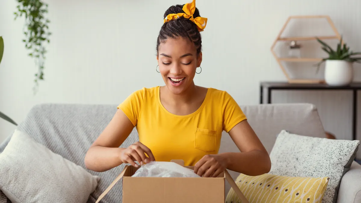 Happy black woman unpacking box after online shopping