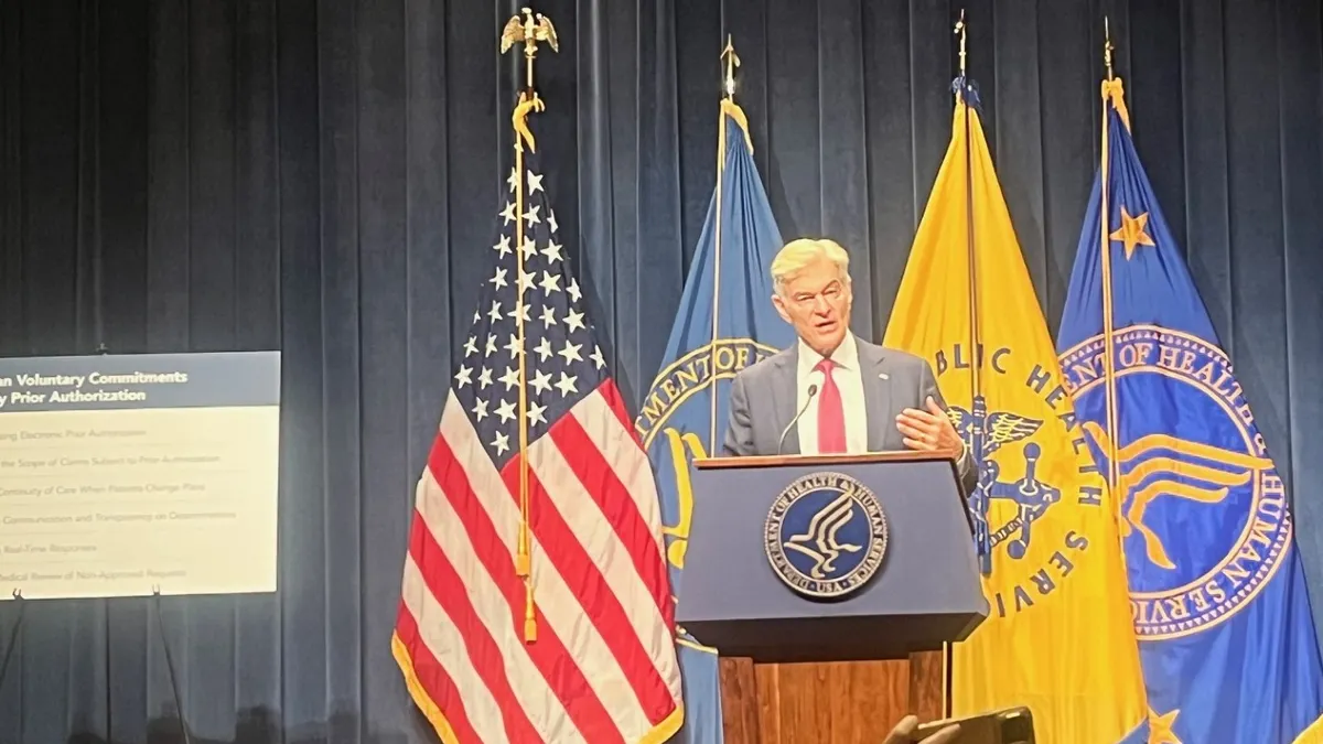 Dr. Mehmet Oz stands behind a podium in front of the American flag.