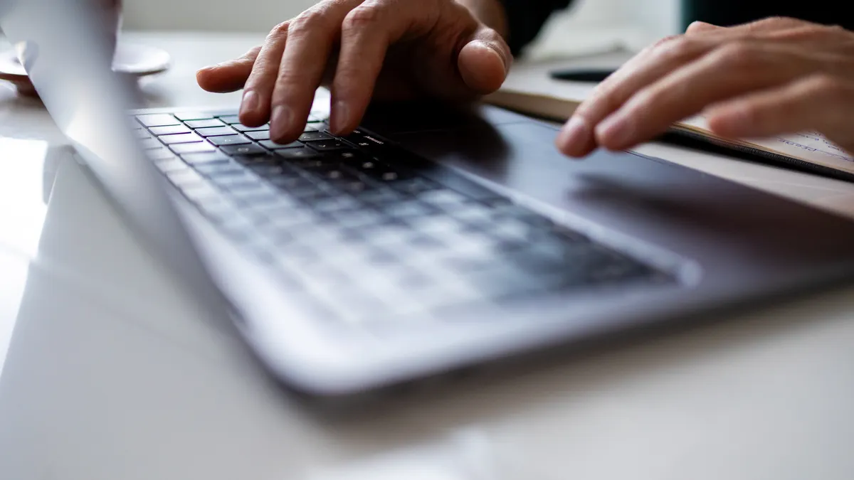 close up of a man typing on a laptop