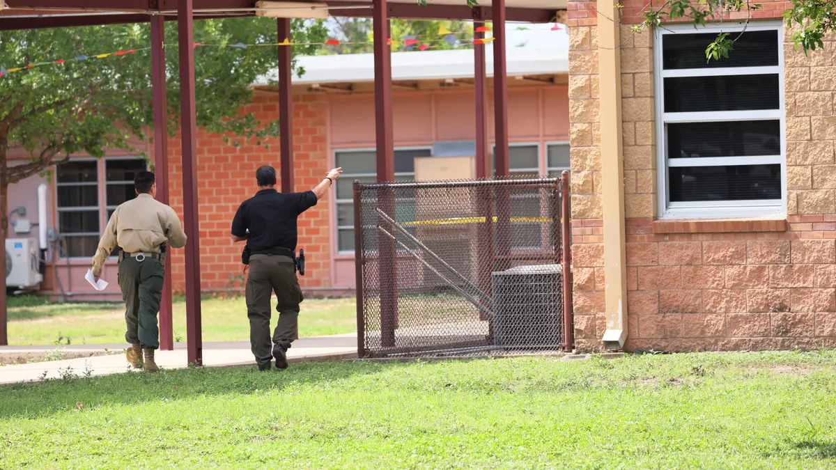 Two police officers walk toward Robb Elementary School in Uvalde, Texas