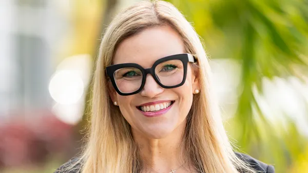 A photograph of a person wearing black glasses and a black blazer.