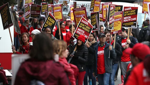 Kaiser Permanente mental health workers on strike carry signs