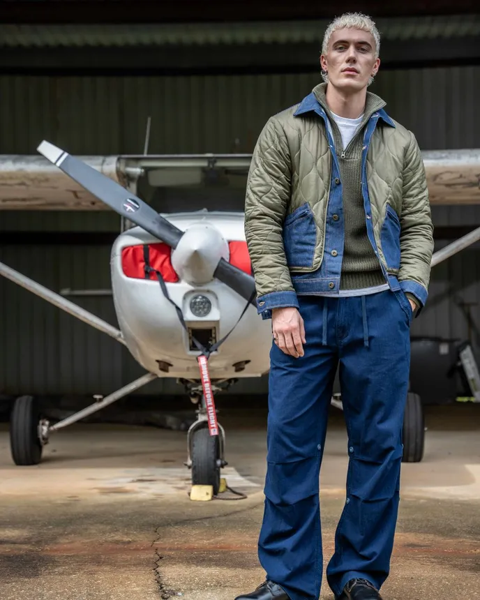 A model stands by an airplane wearing items from the Lee and Alpha Industries collab.