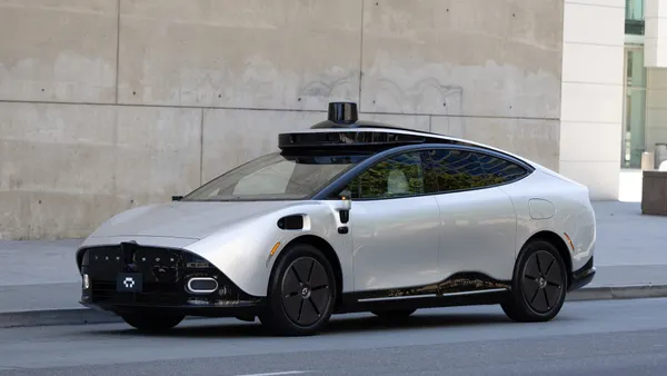 A silver Tensor RoboCar parked in front of a concrete wall.