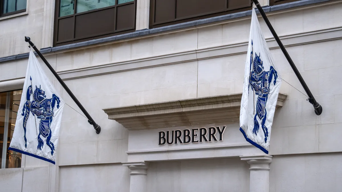 The signage on a Burberry storefront is pictured in a closeup, with two Burberry flags on either side.