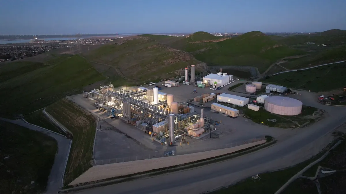 An aerial image of an industrial facility on top of grassy mounds at dusk.