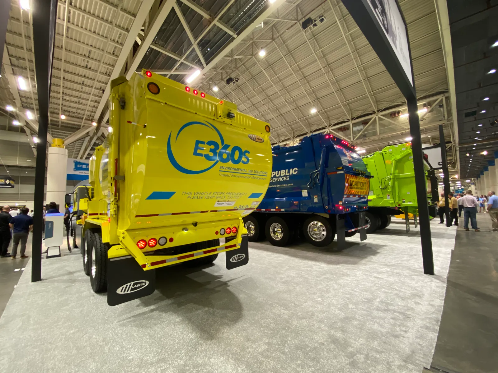 Three refuse haulers lined up on a showroom floor