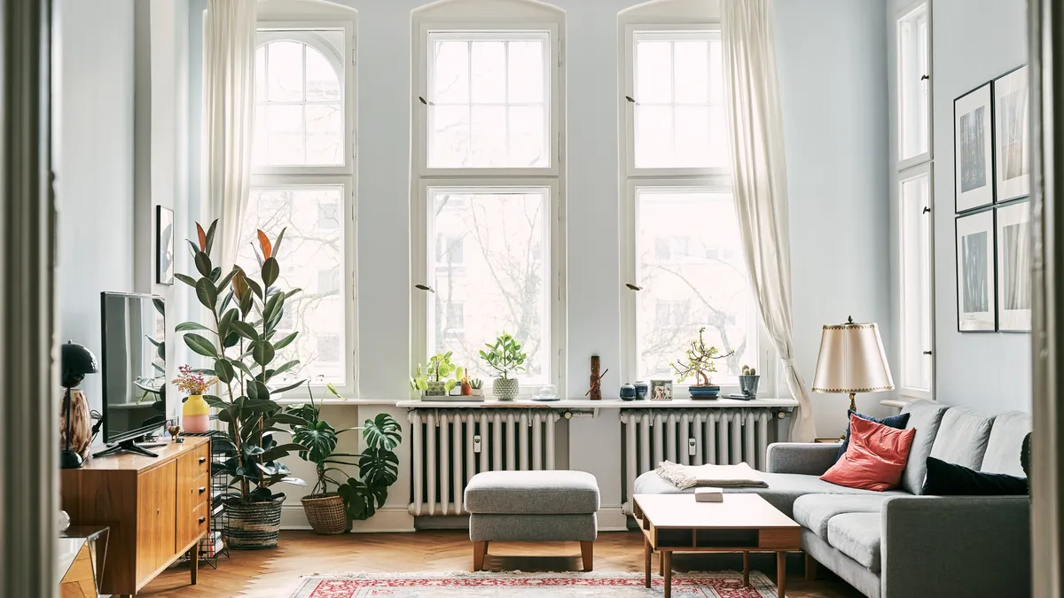 A living room with a high ceiling and light green walls.