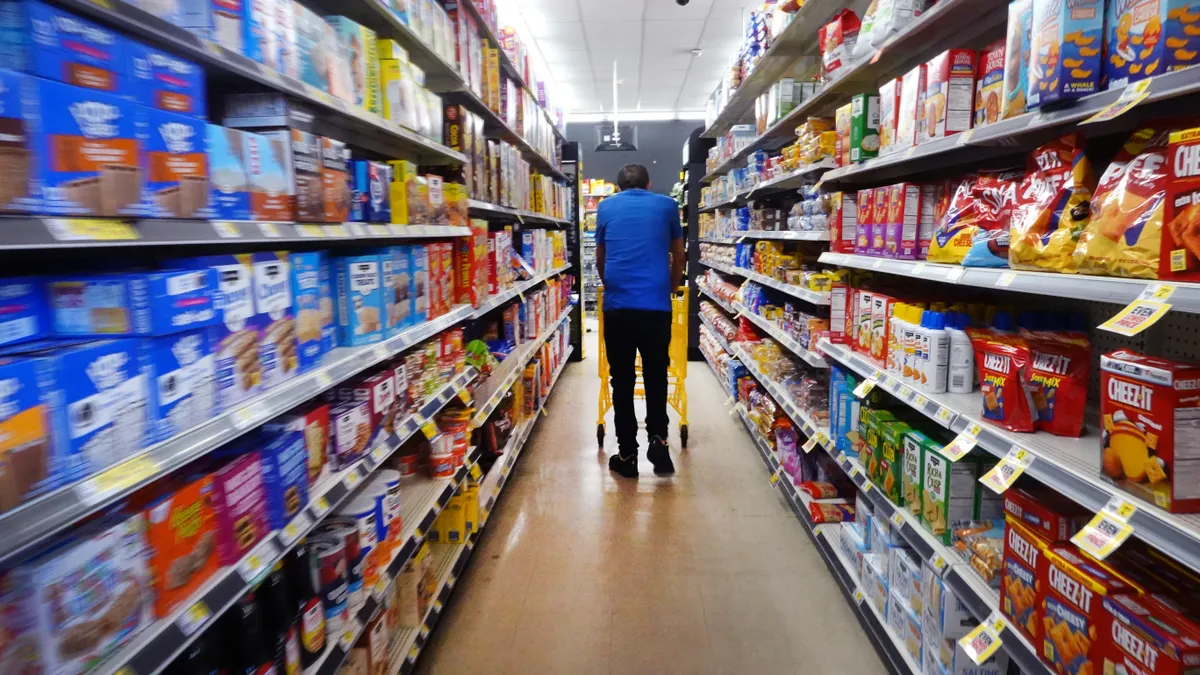 A customer walks down a grocery aisle.