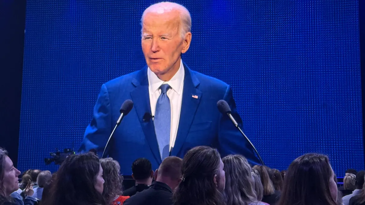 Attendees watch former President Joe Biden as he speaks on stage.