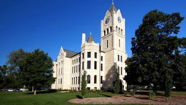 A stone building with turrets on a green lawn under blue sky.