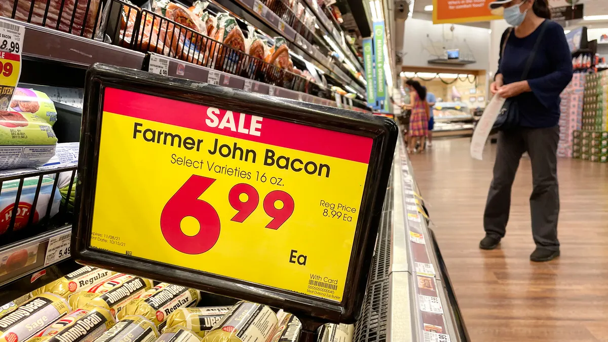 A person shops in the meat section of a grocery store.