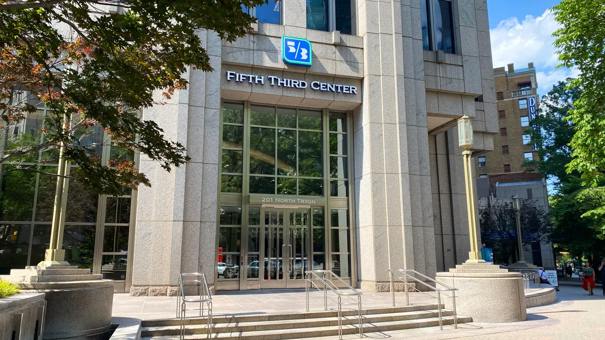 A stone building facade with the Fifth Third logo and "Fifth Third Center" above the entrance is shown, with tree branches in the foreground.