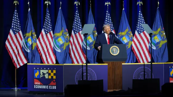 President Donald Trump speaks at a podium with a seal in front of U.S. and other flags.