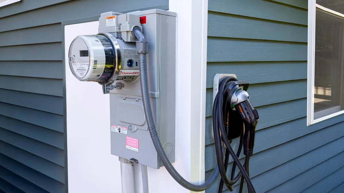 ConnectDER's EV meter socket adapter installed on the side of a house with an EV charger attached to the meter.