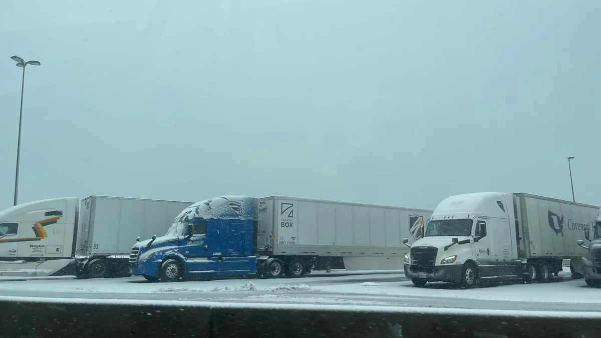 A snowstorm covers tractor-trailers parked at a rest stop in December 2024.