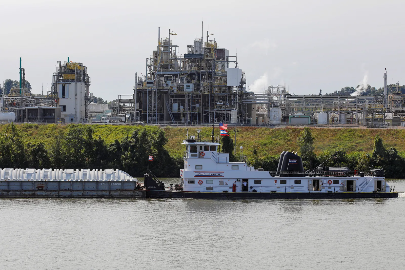 A towboat passes an industrial chemical plant.