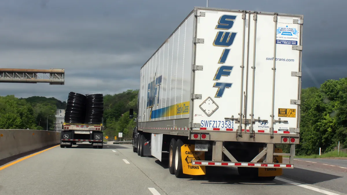 A Swift trailer on an interstate in 2024 in the right lane near a flatbed.