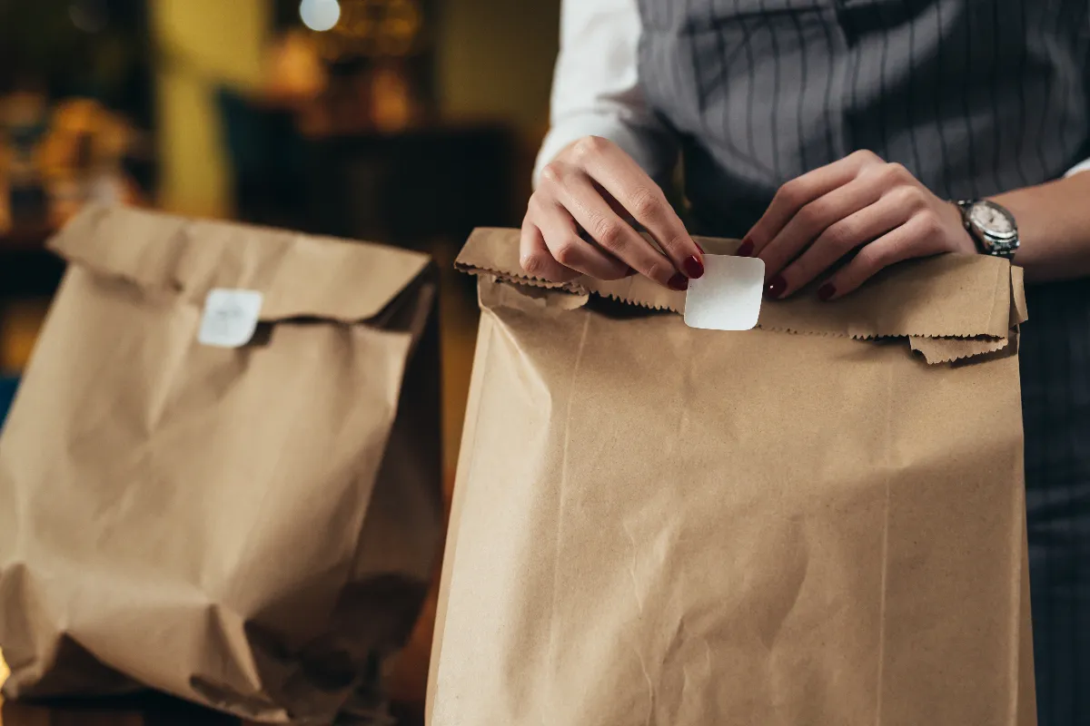 An image of a woman preparing bags for takeout in a restaurant