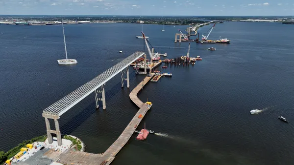 An aerial view shows construction of a bridge over a body of water.