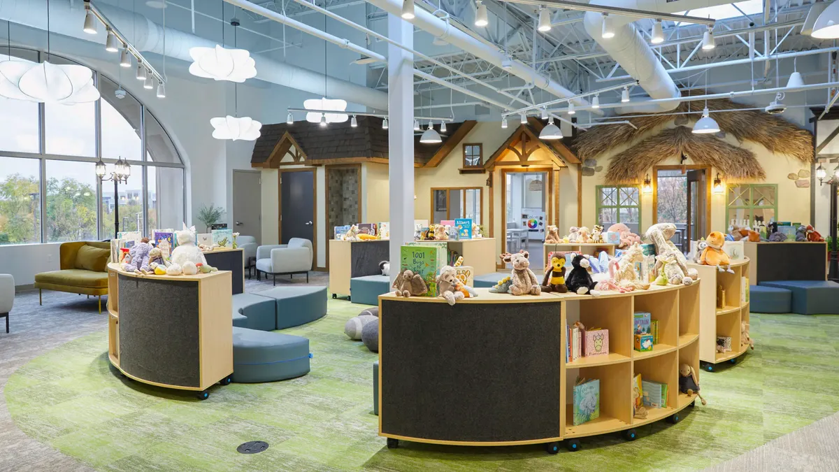 A view into a large open room with children's bookshelves and seating, and faux storefronts in the background.