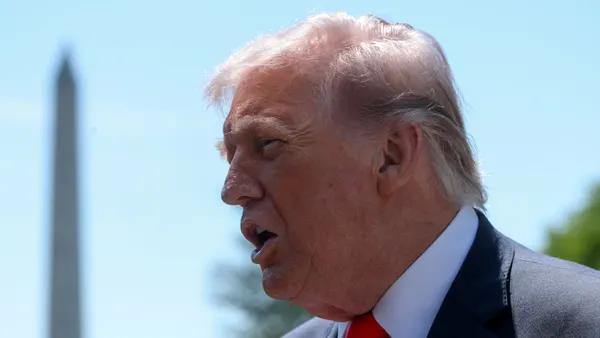 President Donald Trump speaks with the Washington Monument in the distance.
