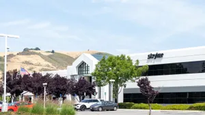 The Stryker logo is displayed on an office building with hills in the background.