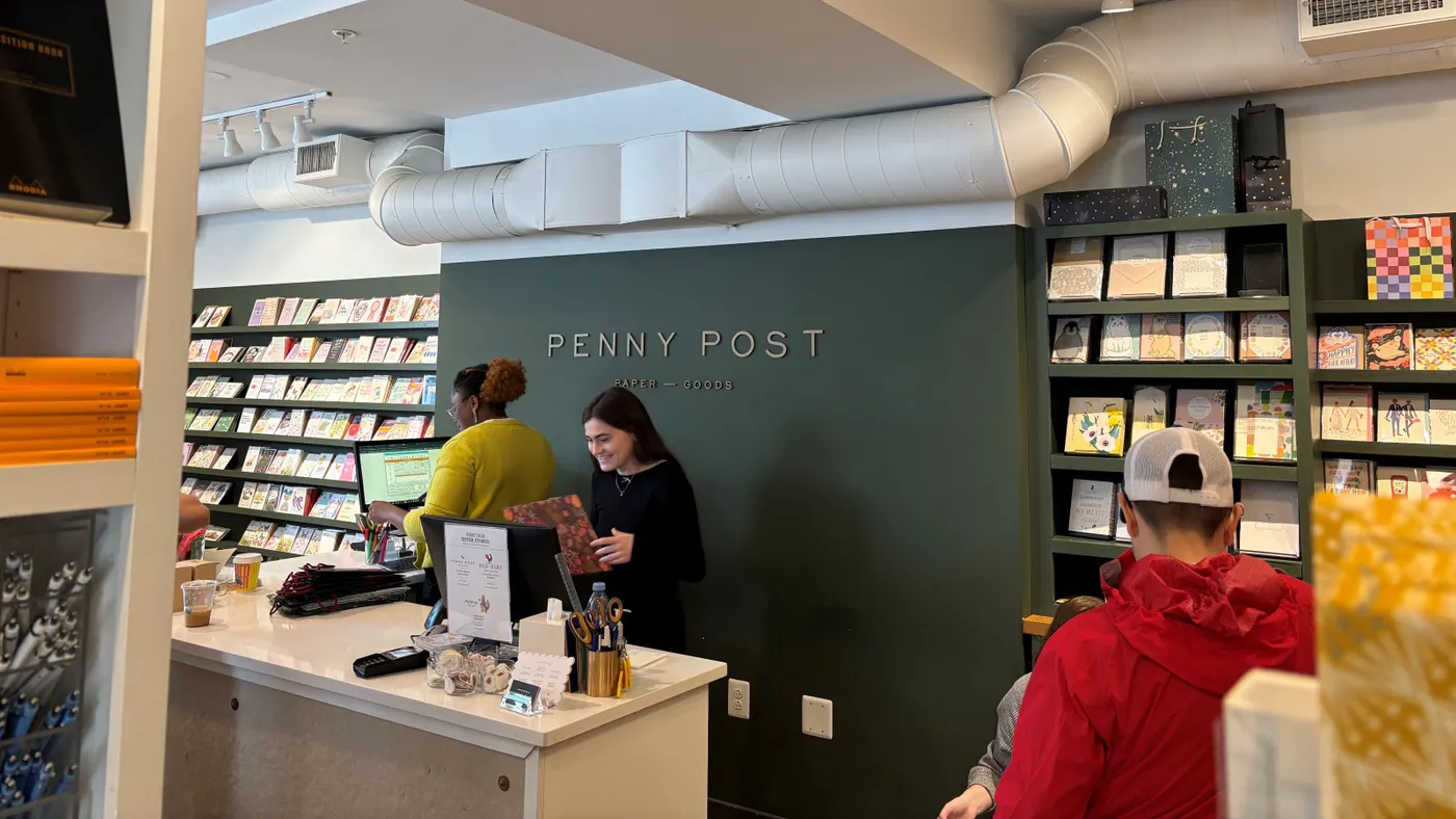 Two cashiers behind the counter of a paper goods store, Penny Post.
