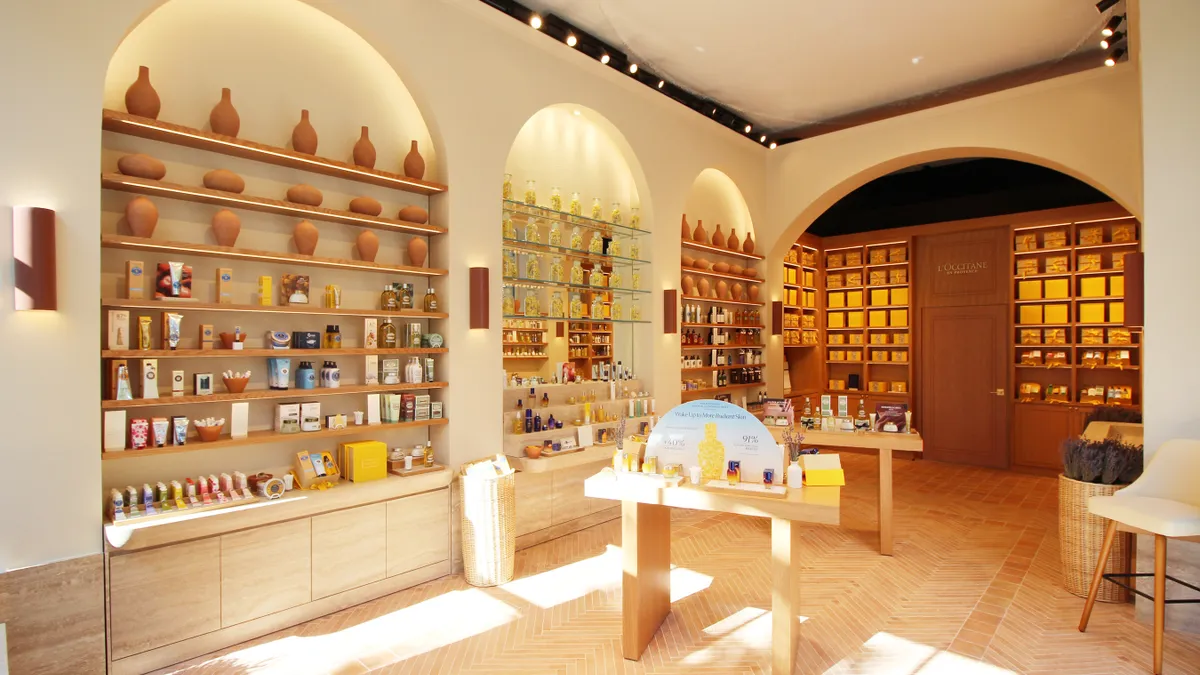 A warm-tinted room with beauty products on display tables and on shelves on the wall.