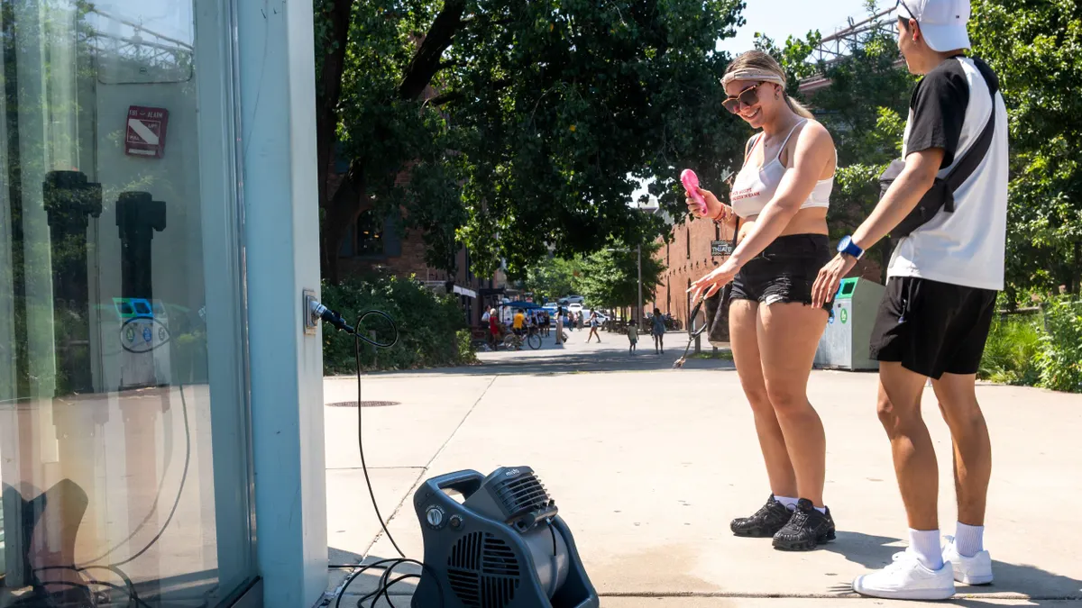 People pause in front of a cooling mister during a heat wave.