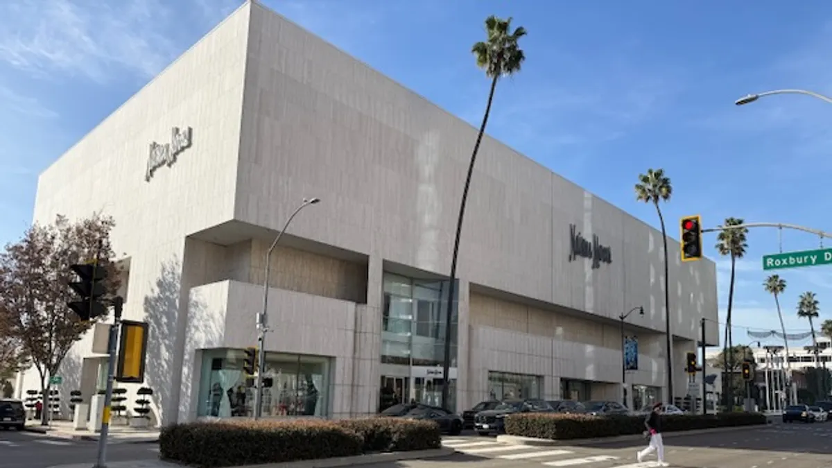 A palm tree in front of a light-colored building, against a blue sky.